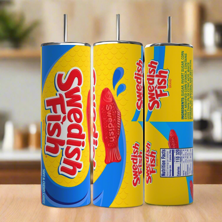 Three cylindrical Swedish Fish 20oz Stainless Steel Skinny Tumblers by Kreative Kreationz are displayed, each featuring a vibrant candy design. Predominantly blue and yellow with red fish graphics and the text "Swedish Fish," one tumbler comes with nutritional facts on the back. All have metal straws, making them perfect stainless steel tumblers for any occasion.