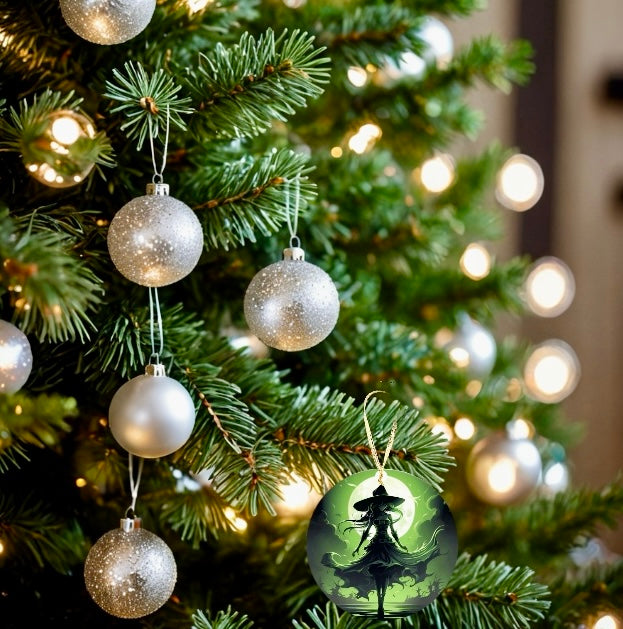 A decorated Christmas tree with golden lights and shiny silver baubles. Among the holiday decor, one Kreative Kreationz Wicked Witch Christmas Tree Ornament stands out, featuring a silhouette of a witch against a green, mystical background.