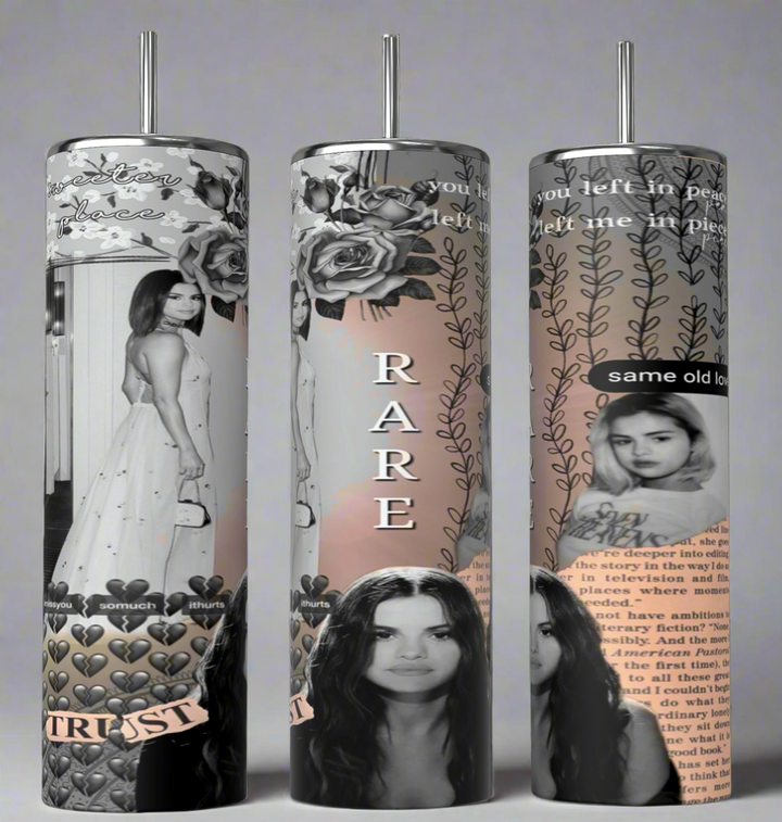 Three tall tumblers are decorated with images of Selena Gomez in different poses; one in a white dress, one with a serious expression, and one in casual attire. The designs, reminiscent of intricate Stanley cups, are embellished with flowers, leaves, hearts, and text like "Rare," "Trust," "same old love,” and "you left me in pieces.