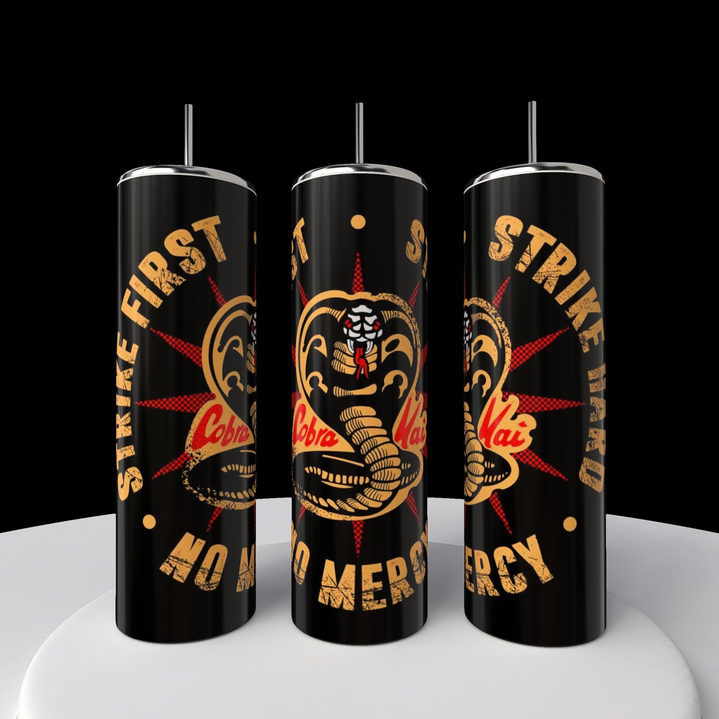 Three sleek black stainless steel Kreative Kreationz tumblers, with straws and adorned with a yellow cobra logo and the text "Strike First, Strike Hard, No Mercy," are showcased on a round white platform against a striking black background.