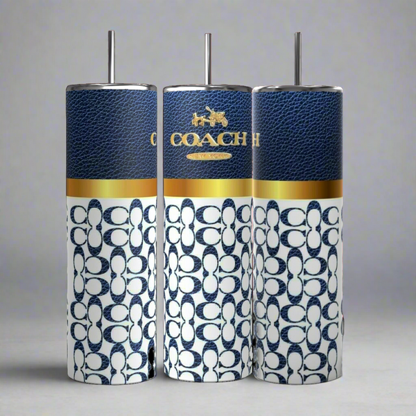 Three Coach-inspired dark blue 20oz tumblers from Kreative Kreationz, each accompanied by a metal straw, are displayed. These tumblers showcase a textured dark blue upper section featuring the "COACH" logo in gold and a white lower section adorned with a blue Coach pattern. The tumblers are aligned side by side against a grey background.