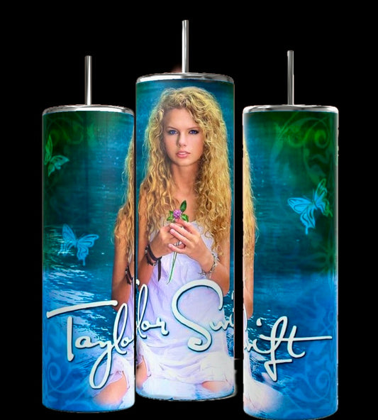 The Debut Taylor Swift 20oz Tumblers by Kreative Kreationz come in a set of three, each with reusable metal straws and spill-proof lids. They feature an image of a woman with curly blonde hair holding a green object, set against a background of green swirls and butterflies. The name "Taylor Swift" is prominently displayed at the bottom.