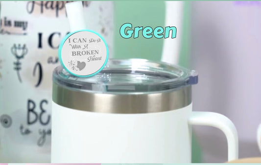 A white insulated mug features a clear lid and personalized straw topper from Kreative Kreationz. The text "Green" is above the mug, which has a circular sticker saying "I can do it with a broken heart" from the I Can Do It With A Broken Heart Straw Topper collection.