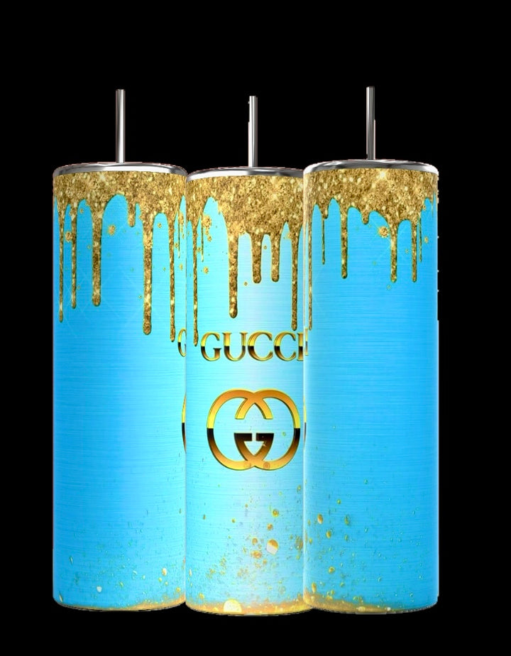 The Kreative Kreationz "Gucci Blue Drip 20oz Tumbler" is a set of three cylindrical tumblers featuring spill-proof metallic lids and straws, with a turquoise and gold drip design over a sleek black backdrop displaying a logo that resembles Gucci, perfectly merging style with functionality.