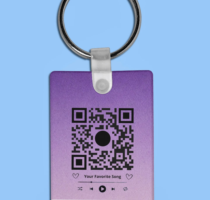 Discover the "Our Song Keychain" by Kreative Kreationz, featuring a purple gradient tag with a working QR code at the center. Media control icons and "Your Favorite Song" in bold black text enhance its charm on a solid light blue background.