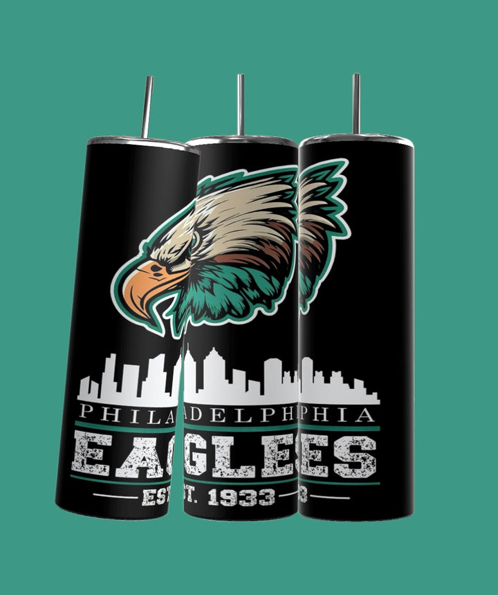 Three black Kreative Kreationz EAGLES Football 20oz Skinny Tumblers feature the Philadelphia Eagles logo in green, silver, and white. "Philadelphia Eagles Est. 1933" is inscribed with a city skyline above "Eagles." Each comes with a spill-proof lid and reusable straw.