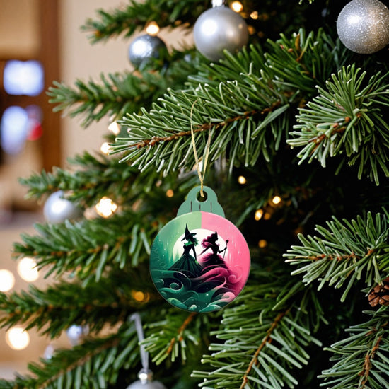 A close-up of a decorated Christmas tree highlights Kreative Kreationz's Wicked Christmas Tree Ornament, showcasing a whimsical illustration of a witch and a girl in a magical forest. The tree is adorned with silver baubles and pine needles, making it ideal for festive decorators seeking enchanting holiday decor.