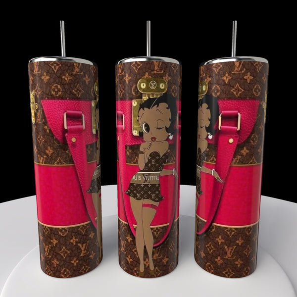 Kreative Kreationz presents three Betty B Coach 20oz Skinny Tumblers, showcasing the iconic Betty Boop in a chic outfit against a pink and brown patterned backdrop with strap details. Each sublimated tumbler includes a metallic lid and straw, displayed on a round white platform.