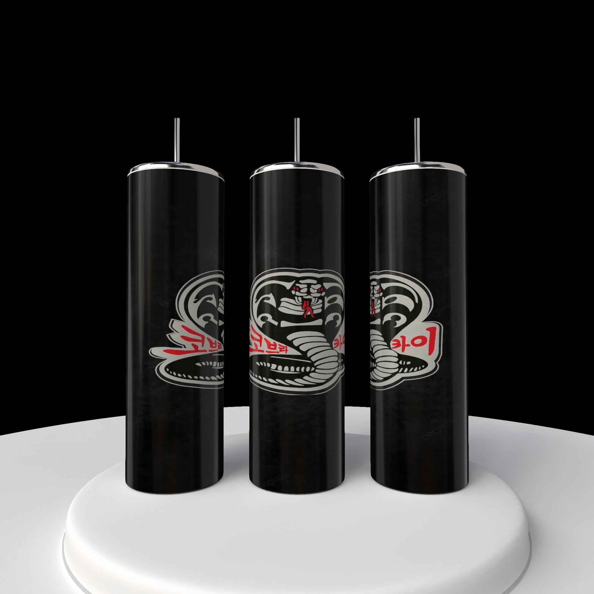 Three slender black Kobra Kai 20oz Stainless Steel Tumblers from Kreative Kreationz are displayed vertically on a circular white platform against a midnight backdrop. Each tumbler resembles spray cans with snake illustrations and red and white text, adding intrigue and elegance.