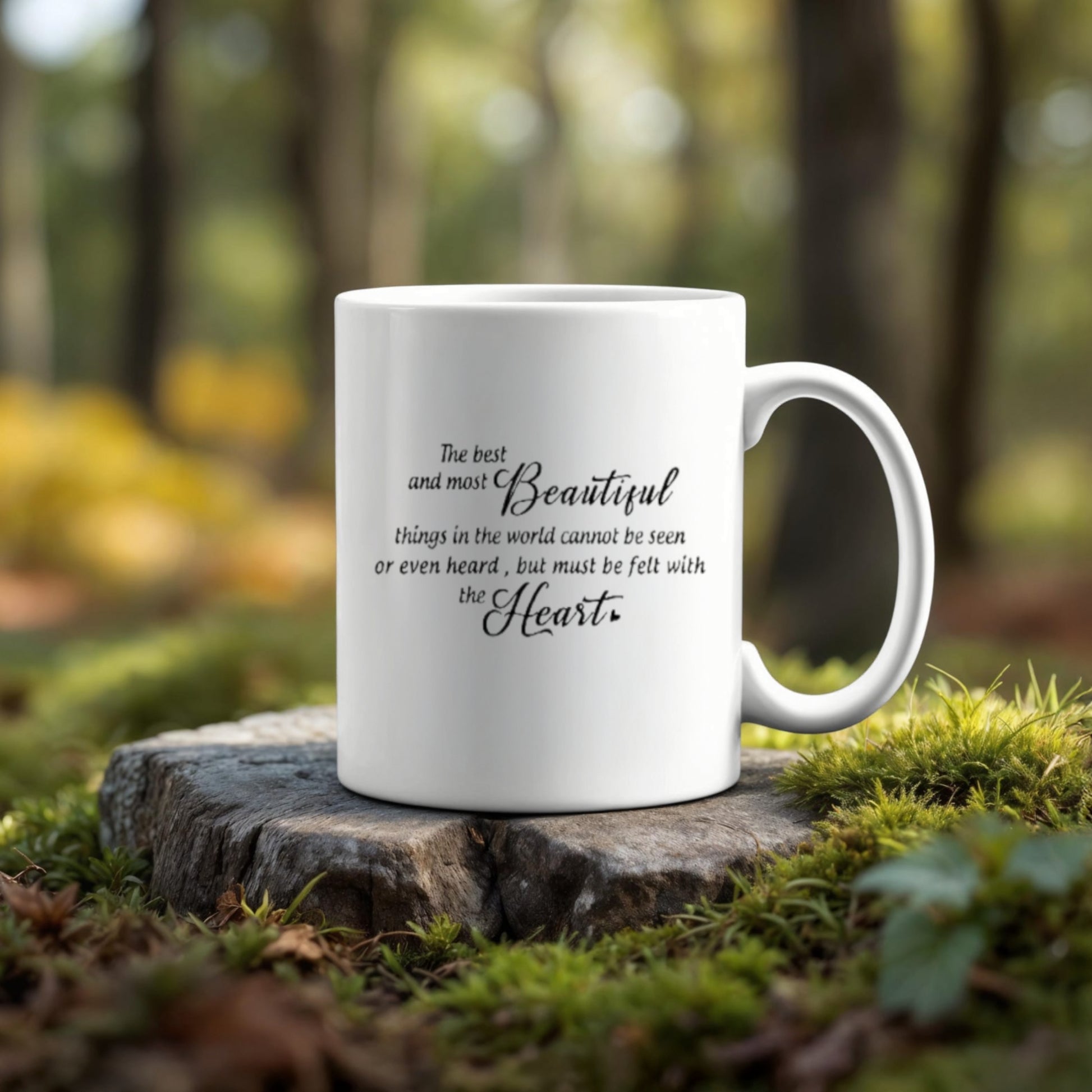 The Personalized Couples Ceramic Mug by Kreative Kreationz, featuring the heartfelt quote "The best and most beautiful things in the world cannot be seen or even heard, but must be felt with the heart," sits on a tree stump in a serene forest—perfect for adding customized heartwarming options.