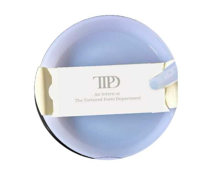 A circular blue ashtray holds an open white matchbox that reads "The Tortured Poets Department Intern" by Kreative Kreationz. The Stanley Plate/Topper matchbox, known for its durability and safeness, is placed across the ashtray with the matchsticks visible on the sides.